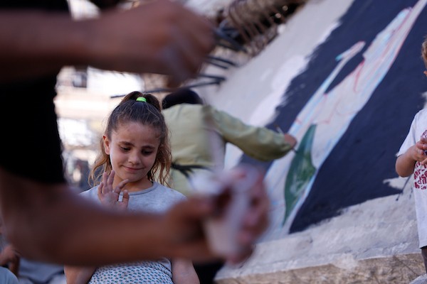 فنانون فلسطينيون يرسمون جدارية لمغني الراب الأمريكي ماكليمور على جدار مبنى دمرته الحرب في مدينة غزة، في 17 سبتمبر/أيلول 2026. تصوير: عبد الله أبو الخير