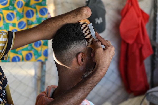 الحلاق جهاد المبحوح (38 عاماً) يواصل عمله داخل خيمة في مخيم النصيرات وسط قطاع غزة، في 20 سبتمبر/أيلول 2026، بعد فقدانه إحدى يديه إثر إصابته في غارة إسرائيلية. (صورة: حسن الجدي)