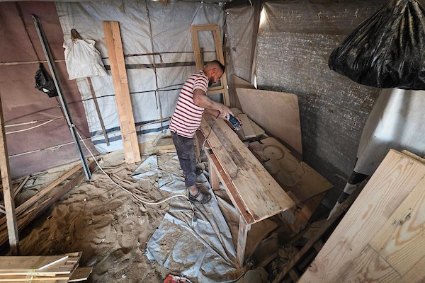 النجار الفلسطيني إياد أبو عامر يصنع مقاعد دراسية من أخشاب انتُشلت من أنقاض المنازل المدمرة وصناديق الإغاثة وقطع المعادن في خان يونس جنوب قطاع غزة، مع انطلاق العام الدراسي الجديد في 21 سبتمبر/أيلول 2026. تصوير: طارق محمد.