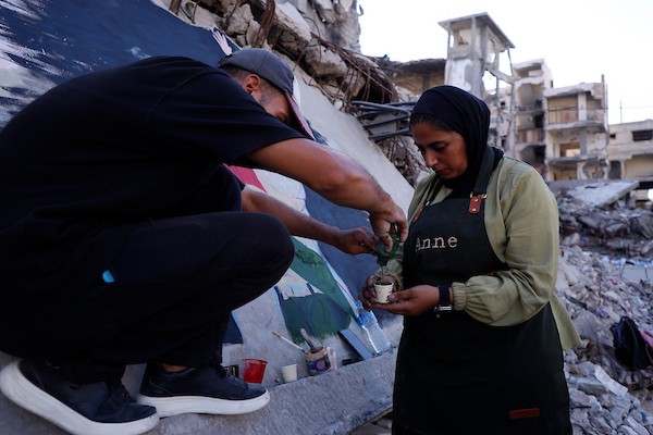 فنانون فلسطينيون يرسمون جدارية لمغني الراب الأمريكي ماكليمور على جدار مبنى دمرته الحرب في مدينة غزة، في 17 سبتمبر/أيلول 2026. تصوير: عبد الله أبو الخير