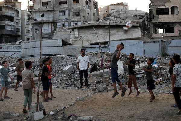 أطفال فلسطينيون يلعبون الكرة الطائرة على ملعب أُقيم بين أنقاض المباني التي دمرتها الحرب في مدينة غزة في 16 سبتمبر/أيلول 2026. صورة: بلال أسامة