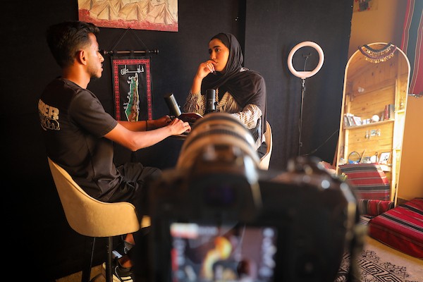 تعمل الصحفية والمذيعة الفلسطينية تالا درويش، داخل استوديو مؤقت بنته من ألواح خشبية مأخوذة من صناديق المساعدات في مخيم النصيرات للاجئين وسط قطاع غزة.تصوير: معز صالحي