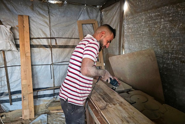 النجار الفلسطيني إياد أبو عامر يصنع مقاعد دراسية من أخشاب انتُشلت من أنقاض المنازل المدمرة وصناديق الإغاثة وقطع المعادن في خان يونس جنوب قطاع غزة، مع انطلاق العام الدراسي الجديد في 21 سبتمبر/أيلول 2026. تصوير: طارق محمد.