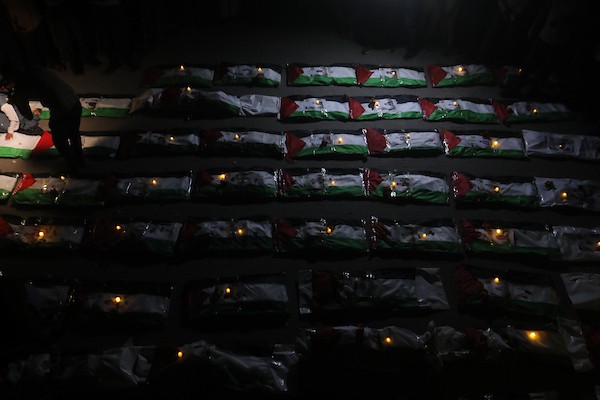 فلسطينيون يتجمعون حول رفات 106 ضحايا غُطيت بالأعلام الفلسطينية وأضيئت إلى جانبها الشموع، خلال مراسم وداع في حي الزيتون بمدينة غزة، 5 أيلول/سبتمبر 2026. تصوير: بلال أسامة