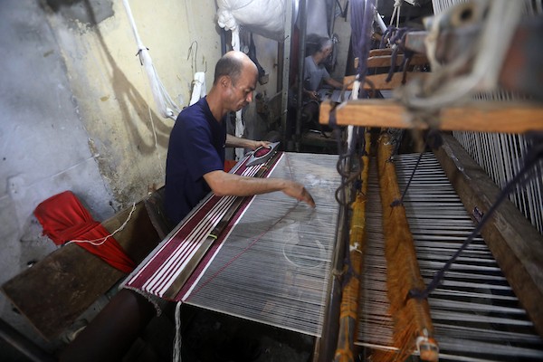عمال فلسطينيون يصنعون السجاد يدويًا باستخدام أدوات بسيطة داخل متجر شرقي مدينة غزة، في 31 آب/أغسطس 2026. (تصوير: بلال أسامة)