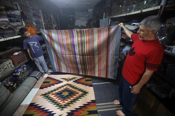 عمال فلسطينيون يصنعون السجاد يدويًا باستخدام أدوات بسيطة داخل متجر شرقي مدينة غزة، في 31 آب/أغسطس 2026. (تصوير: بلال أسامة)