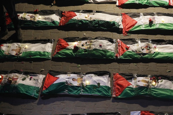 فلسطينيون يتجمعون حول رفات 106 ضحايا غُطيت بالأعلام الفلسطينية وأضيئت إلى جانبها الشموع، خلال مراسم وداع في حي الزيتون بمدينة غزة، 5 أيلول/سبتمبر 2026. تصوير: بلال أسامة