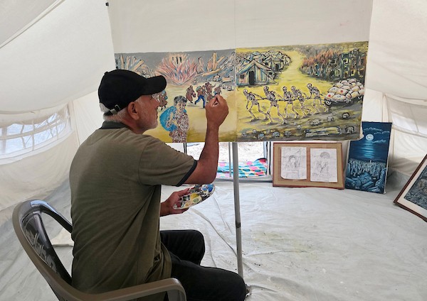 الفنان الفلسطيني جهاد الشرافي يرسم داخل خيمة للنازحين في خان يونس جنوبي قطاع غزة، مشاهد توثق الحرب والجوع ونقص المياه والدمار، في 18 سبتمبر/أيلول 2026. تصوير: طارق محمد