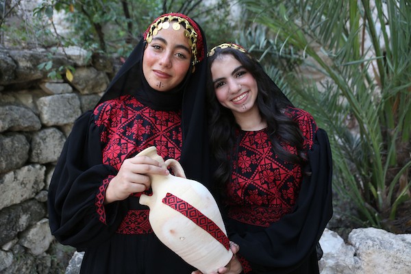 فتيات فلسطينيات يرتدين أزياءً وطنية تقليدية مطرزة بالحرير يقفن على جسر حديدي في الموقع الأثري بمدينة سبسطية، غرب نابلس شمال الضفة الغربية. (تصوير: محمد ناصر )