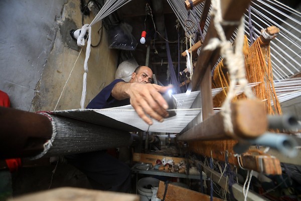 عمال فلسطينيون يصنعون السجاد يدويًا باستخدام أدوات بسيطة داخل متجر شرقي مدينة غزة، في 31 آب/أغسطس 2026. (تصوير: بلال أسامة)