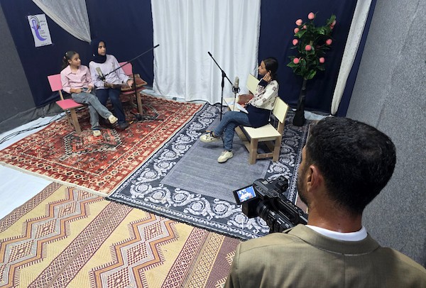 أطفال فلسطينيون يشاركون في إعداد وتقديم برامج لقناة طلائع فلسطين من استوديو متواضع أُقيم داخل خيام النزوح في منطقة مواصي خان يونس. (تصوير: طارق محمد)