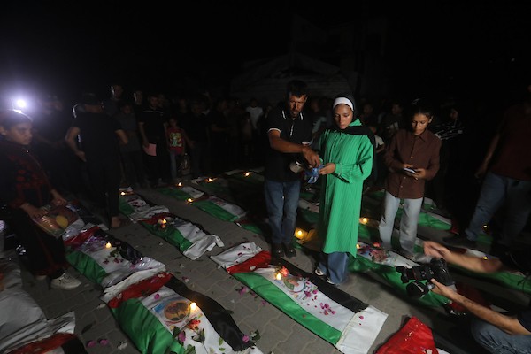 فلسطينيون يتجمعون حول رفات 106 ضحايا غُطيت بالأعلام الفلسطينية وأضيئت إلى جانبها الشموع، خلال مراسم وداع في حي الزيتون بمدينة غزة، 5 أيلول/سبتمبر 2026. تصوير: بلال أسامة