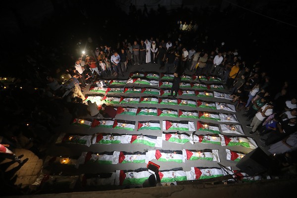 فلسطينيون يتجمعون حول رفات 106 ضحايا غُطيت بالأعلام الفلسطينية وأضيئت إلى جانبها الشموع، خلال مراسم وداع في حي الزيتون بمدينة غزة، 5 أيلول/سبتمبر 2026. تصوير: بلال أسامة