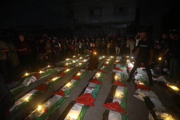 فلسطينيون يتجمعون حول رفات 106 ضحايا غُطيت بالأعلام الفلسطينية وأضيئت إلى جانبها الشموع، خلال مراسم وداع في حي الزيتون بمدينة غزة، 5 أيلول/سبتمبر 2026. تصوير: بلال أسامة