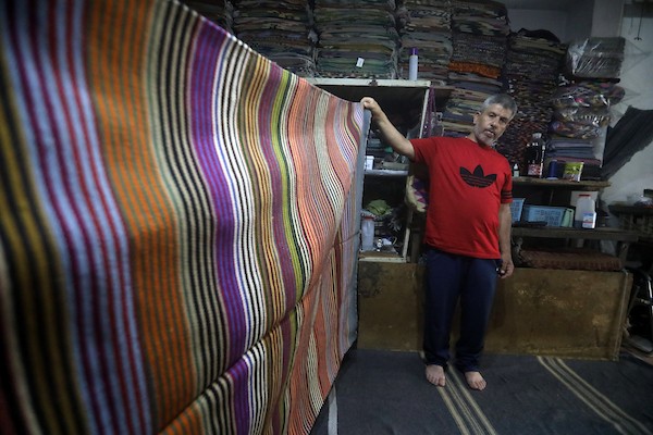 عمال فلسطينيون يصنعون السجاد يدويًا باستخدام أدوات بسيطة داخل متجر شرقي مدينة غزة، في 31 آب/أغسطس 2026. (تصوير: بلال أسامة)