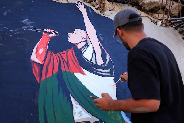 فنانون فلسطينيون يرسمون جدارية لمغني الراب الأمريكي ماكليمور على جدار مبنى دمرته الحرب في مدينة غزة، في 17 سبتمبر/أيلول 2026. تصوير: عبد الله أبو الخير
