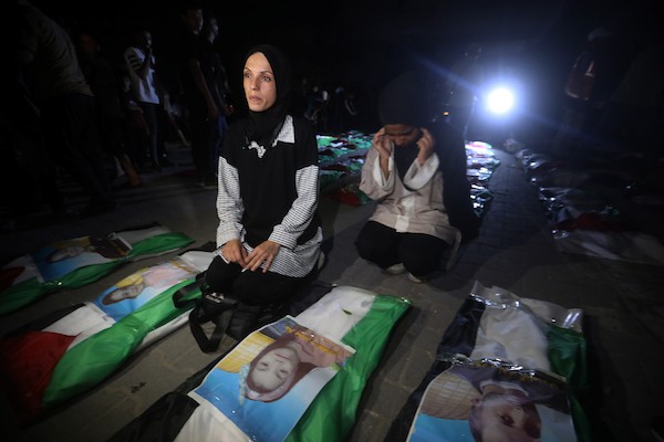 فلسطينيون يتجمعون حول رفات 106 ضحايا غُطيت بالأعلام الفلسطينية وأضيئت إلى جانبها الشموع، خلال مراسم وداع في حي الزيتون بمدينة غزة، 5 أيلول/سبتمبر 2026. تصوير: بلال أسامة