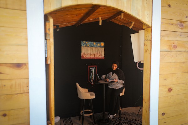 تعمل الصحفية والمذيعة الفلسطينية تالا درويش، داخل استوديو مؤقت بنته من ألواح خشبية مأخوذة من صناديق المساعدات في مخيم النصيرات للاجئين وسط قطاع غزة.تصوير: معز صالحي