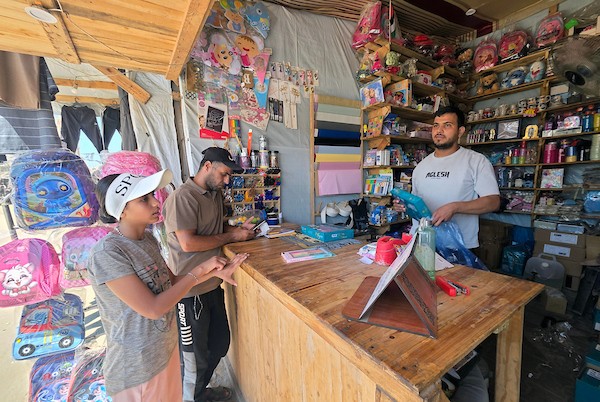 يتسوق فلسطينيون حقائب وأدوات مكتبية ولوازم مدرسية أخرى من أكشاك في سوق خان يونس، 13 سبتمبر/أيلول 2026. (صورة: طارق محمد