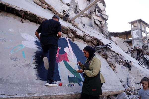 فنانون فلسطينيون يرسمون جدارية لمغني الراب الأمريكي ماكليمور على جدار مبنى دمرته الحرب في مدينة غزة، في 17 سبتمبر/أيلول 2026. تصوير: عبد الله أبو الخير