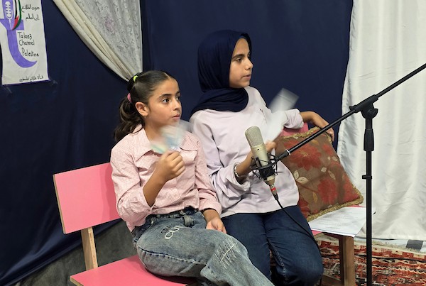 أطفال فلسطينيون يشاركون في إعداد وتقديم برامج لقناة طلائع فلسطين من استوديو متواضع أُقيم داخل خيام النزوح في منطقة مواصي خان يونس. (تصوير: طارق محمد)