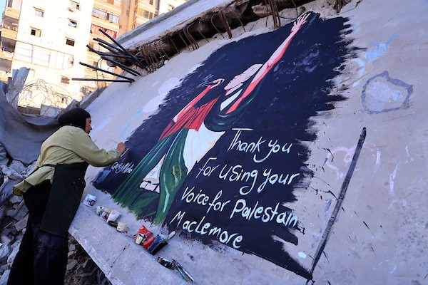 فنانون فلسطينيون يرسمون جدارية لمغني الراب الأمريكي ماكليمور على جدار مبنى دمرته الحرب في مدينة غزة، في 17 سبتمبر/أيلول 2026. تصوير: عبد الله أبو الخير