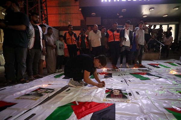 فلسطينيون يشعلون الشموع أمام مستشفى العودة في مخيم النصيرات وسط قطاع غزة، في 28 سبتمبر/أيلول 2026، خلال وداع رفات شهداء. (صورة: معز صالحي)
