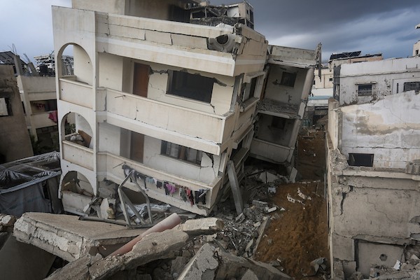 فلسطينيون يتفقدون ممتلكاتهم بين أنقاض مبنى سكني دمره قصف جوي إسرائيلي ليلًا في حي الرمال بمدينة غزة، 11 أكتوبر/تشرين الأول 2026. (تصوير: محمد صالحة)