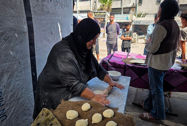 الفلسطيني مازن الدوش يُعدّ الخبز على صاج بدائي بين أنقاض المباني المدمرة في خان يونس، جنوب قطاع غزة، 9 تشرين الأول/أكتوبر 2026. (تصوير: طارق محمد)