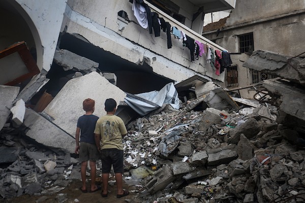 فلسطينيون يتفقدون ممتلكاتهم بين أنقاض مبنى سكني دمره قصف جوي إسرائيلي ليلًا في حي الرمال بمدينة غزة، 11 أكتوبر/تشرين الأول 2026. (تصوير: محمد صالحة)