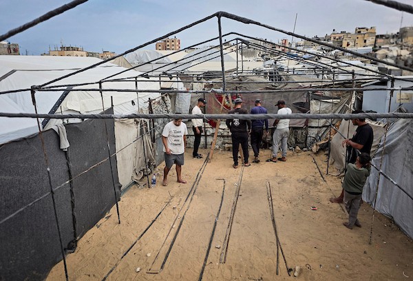 فلسطينيون يستخدمون قضبانًا معدنية انتشلوها من أنقاض منازل مدمرة لإقامة خيام تؤوي عائلات نازحة في منطقة المواصي بخان يونس، في 12 أكتوبر/تشرين الأول 2026، استعدادًا لفصل الشتاء.(تصوير: طارق محمد)