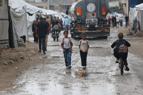 تحت أمطار غزة، يسير فلسطينيون نازحون وسط ظروف معيشية قاسية، فيما يحاول آخرون تغطية خيامهم لمنع تسرب مياه الأمطار إليها، في 18 أكتوبر/تشرين الأول 2026.تصوير: محمد صالحة