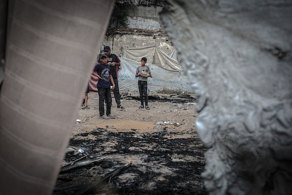 نازحون فلسطينيون يتفقدون بقايا خيامهم وممتلكاتهم التي أتت عليها النيران إثر غارة إسرائيلية قرب مفترق الشجاعية شرقي مدينة غزة، 26 أكتوبر 2026. (تصوير: بلال أسامة)