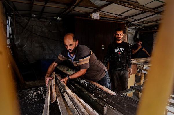 نجارون فلسطينيون يحولون صناديق المساعدات الخشبية إلى مقاعد مدرسية بمدينة غزة، في محاولة لدعم تعليم الأطفال وسط الدمار ونقص المواد الأساسية. (تصوير: محمد صالحة)