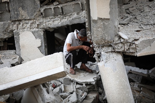 فلسطينيون يتفقدون ممتلكاتهم بين أنقاض مبنى سكني دمره قصف جوي إسرائيلي ليلًا في حي الرمال بمدينة غزة، 11 أكتوبر/تشرين الأول 2026. (تصوير: محمد صالحة)