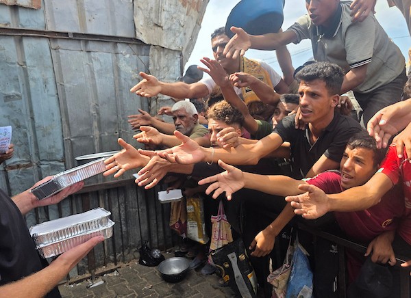 يتجمع فلسطينيون نازحون لتلقي وجبات ساخنة من مطبخ خيري، يُوصف بأنه آخر مطبخ عامل في منطقة المواصي بخان يونس، 2 أكتوبر/تشرين الأول 2026. (صورة: طارق محمد)