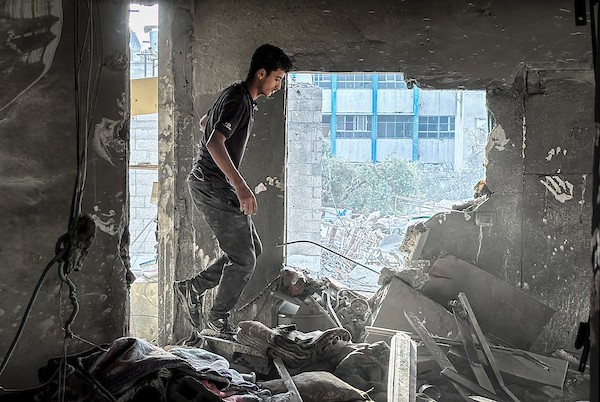فلسطينيون يتفقدون ما تبقى من ممتلكاتهم وسط أنقاض مبنى سكني استهدفته غارة جوية إسرائيلية في مخيم المغازي للاجئين وسط قطاع غزة، يوم 16 أكتوبر/تشرين الأول 2026. (تصوير: أحمد إبراهيم)