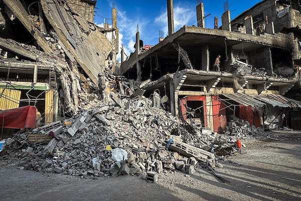 فلسطينيون يتفقدون ما تبقى من ممتلكاتهم وسط أنقاض مبنى سكني استهدفته غارة جوية إسرائيلية في مخيم المغازي للاجئين وسط قطاع غزة، يوم 16 أكتوبر/تشرين الأول 2026. (تصوير: أحمد إبراهيم)