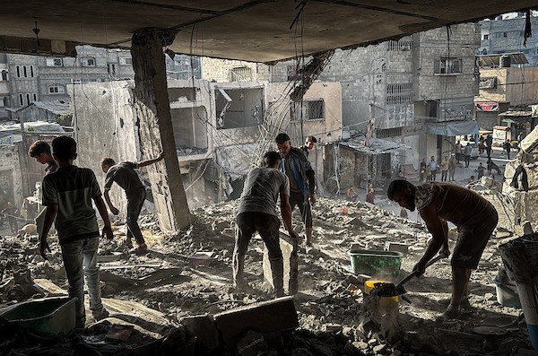 فلسطينيون يتفقدون ما تبقى من ممتلكاتهم وسط أنقاض مبنى سكني استهدفته غارة جوية إسرائيلية في مخيم المغازي للاجئين وسط قطاع غزة، يوم 16 أكتوبر/تشرين الأول 2026. (تصوير: أحمد إبراهيم)