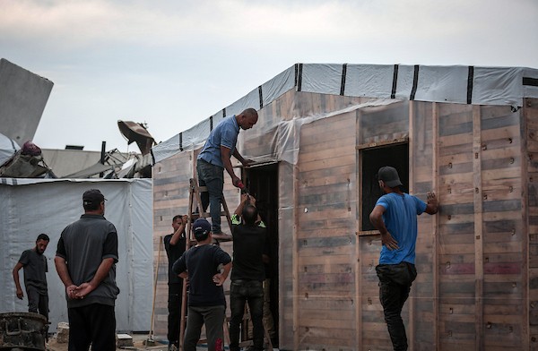 الفلسطيني هشام حميد يبني مأوى لعائلته من أخشاب المساعدات والطين قرب أنقاض منزله غرب مدينة غزة، استعدادًا لبرد الشتاء، 28 أكتوبر/تشرين الأول 2026. (تصوير: محمد صالحة)