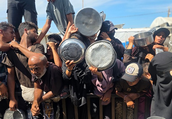 يتجمع فلسطينيون نازحون لتلقي وجبات ساخنة من مطبخ خيري، يُوصف بأنه آخر مطبخ عامل في منطقة المواصي بخان يونس، 2 أكتوبر/تشرين الأول 2026. (صورة: طارق محمد)