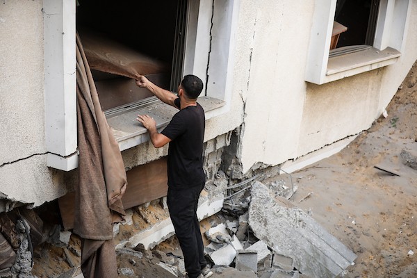 فلسطينيون يتفقدون ممتلكاتهم بين أنقاض مبنى سكني دمره قصف جوي إسرائيلي ليلًا في حي الرمال بمدينة غزة، 11 أكتوبر/تشرين الأول 2026. (تصوير: محمد صالحة)