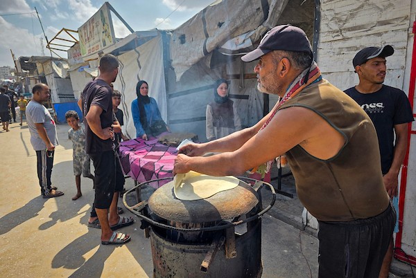 الفلسطيني مازن الدوش يُعدّ الخبز على صاج بدائي بين أنقاض المباني المدمرة في خان يونس، جنوب قطاع غزة، 9 تشرين الأول/أكتوبر 2026. (تصوير: طارق محمد)