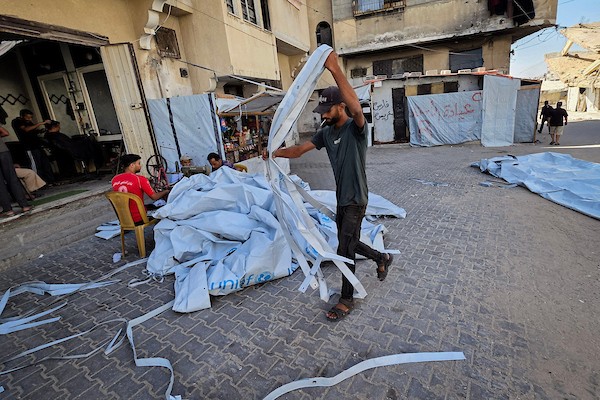 الخياط الفلسطيني شعبان الطباش يصلح أغطية بلاستيكية وقماشًا مشمعًا لتقوية خيام النازحين وحمايتها من برد الشتاء وأمطاره، في خان يونس جنوب قطاع غزة، 4 أكتوبر/تشرين الأول 2026. (تصوير: طارق محمد)