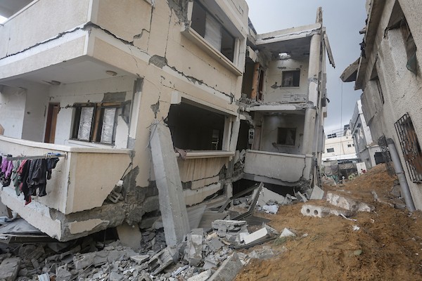 فلسطينيون يتفقدون ممتلكاتهم بين أنقاض مبنى سكني دمره قصف جوي إسرائيلي ليلًا في حي الرمال بمدينة غزة، 11 أكتوبر/تشرين الأول 2026. (تصوير: محمد صالحة)