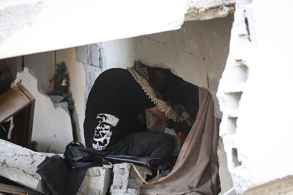 فلسطينيون يتفقدون ممتلكاتهم بين أنقاض مبنى سكني دمره قصف جوي إسرائيلي ليلًا في حي الرمال بمدينة غزة، 11 أكتوبر/تشرين الأول 2026. (تصوير: محمد صالحة)