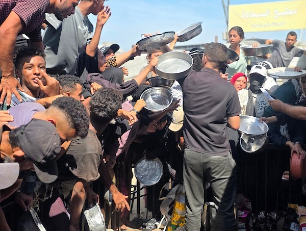 يتجمع فلسطينيون نازحون لتلقي وجبات ساخنة من مطبخ خيري، يُوصف بأنه آخر مطبخ عامل في منطقة المواصي بخان يونس، 2 أكتوبر/تشرين الأول 2026. (صورة: طارق محمد)