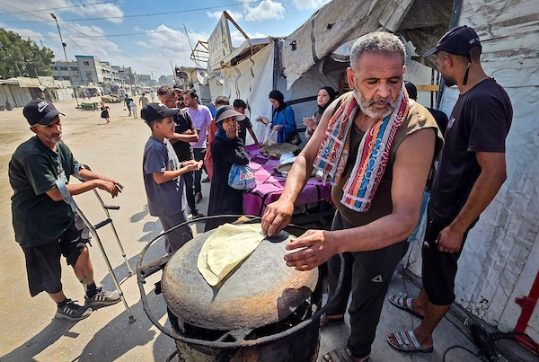 الفلسطيني مازن الدوش يُعدّ الخبز على صاج بدائي بين أنقاض المباني المدمرة في خان يونس، جنوب قطاع غزة، 9 تشرين الأول/أكتوبر 2026. (تصوير: طارق محمد)