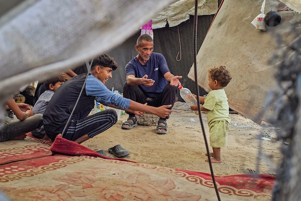 عائلات نازحة تقيم داخل خيام نُصبت بين القبور في إحدى مقابر خان يونس جنوبي قطاع غزة، في 14 أكتوبر/تشرين الأول 2026. (تصوير: طارق محمد)