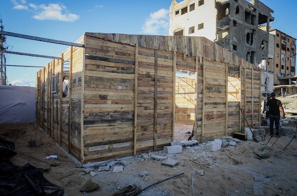 الفلسطيني هشام حميد يبني مأوى لعائلته من أخشاب المساعدات والطين قرب أنقاض منزله غرب مدينة غزة، استعدادًا لبرد الشتاء، 28 أكتوبر/تشرين الأول 2026. (تصوير: محمد صالحة)